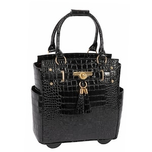 May include: A black handbag with a glossy crocodile skin texture, featuring two top handles, gold-toned hardware, a central turn-lock closure, and a decorative tassel hanging from the front. The bag has side pockets and a structured base.