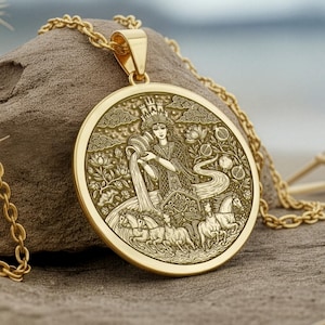 Op de afbeelding: Een gouden ketting met een gedetailleerd gegraveerd ontwerp. De ronde hanger toont een figuur die water giet, omringd door andere figuren en bloemmotieven. De ketting is ook goudkleurig, wat een samenhangend en elegant uiterlijk creëert. De hanger is ongeveer 3 cm in diameter.