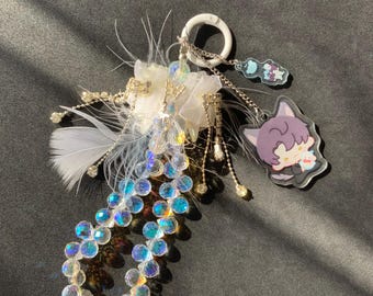 May include: A decorative keychain featuring a white flower, iridescent beads, and a cartoon character charm. The keychain includes white feathers, silver chains, and a clear, iridescent bead strand. The charm depicts a purple-haired character.
