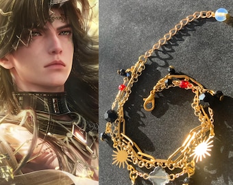 May include: Gold-toned bracelet with multiple chains, featuring black and red beads, sun-shaped charms, and a clear, faceted charm. The bracelet has a lobster clasp closure and a delicate chain with a white bead at the end. The background is dark.