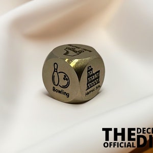 May include: A silver metal six-sided dice with different activities engraved on each side. The side shown in the image has a bowling pin and ball with the word "Bowling" underneath. The text "The Decision Dice Official" is visible in the bottom right corner of the image.