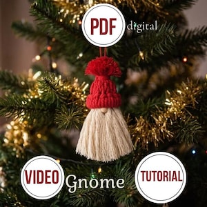 Könnte beinhalten: Ein hängender Weihnachtsbaumschmuck in Form eines Wichtels mit einer roten gehäkelten Mütze und einem langen beigen Faserbart. Das Bild enthält kreisförmige Texteinblendungen mit PDF digital, VIDEO, TUTORIAL sowie das Wort Gnome in Weiß.