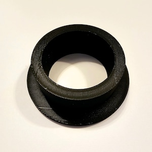 May include: A black plastic ring with a smooth, rounded outer edge and a slightly raised inner edge. The ring has a textured surface.
