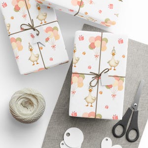 May include: White gift wrap with a repeating pattern of a goose wearing a party hat, balloons, and gift boxes. The gifts are tied with brown twine and a white tag. A ball of twine, scissors, and blank tags are also visible.