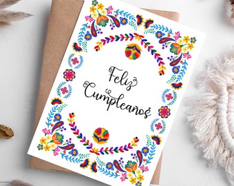 May include: A white card with a colorful floral border and the text "Feliz Cumpleaños" in black cursive writing.