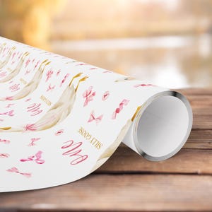 May include: White wrapping paper roll featuring a whimsical design with illustrations of geese, pink bows, and the text "Silly Goose". The design includes the word "One" in a cursive font. The paper is rolled up, showing the metallic silver edge.