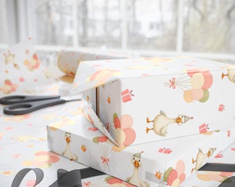 May include: White gift boxes wrapped in patterned paper featuring cartoon geese with party hats, balloons, and gift boxes. A roll of matching wrapping paper and scissors are visible. A black ribbon is in the foreground.