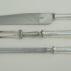 May include: A set of three silver-plated serving utensils, including a carving knife, a two-pronged fork, and a carving knife. The handles are all the same style, with a rounded, slightly flared end.