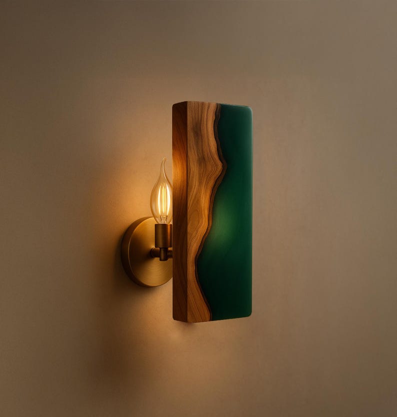 May include: A wall sconce featuring a wooden frame with a live edge design and a rectangular green resin inlay. The sconce has a brass-colored base and a vintage-style light bulb.