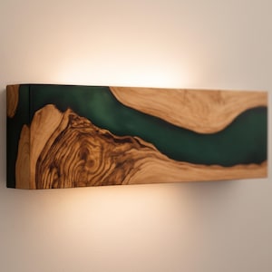 May include: A rectangular wooden wall sconce with a dark green resin river design. The wood grain is visible, and the sconce is mounted on a light-colored wall. The sconce is approximately 18 inches long.