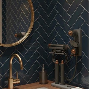 Può includere: Interno bagno con parete piastrellata blu navy e piano d'appoggio in legno. Un rubinetto e una cornice dello specchio dorati completano il design. Include un lavandino bianco, un dosatore di sapone e un organizer per strumenti per lo styling dei capelli.