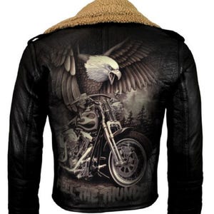 Pode incluir: Jaqueta de couro preta com gola de pele sintética marrom. A jaqueta apresenta uma estampa gráfica de uma águia voando sobre uma motocicleta com o texto "Feel the Thunder".
