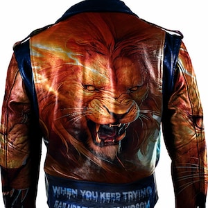 以下が含まれることがあります： 青い襟と袖が付いた茶色の革ジャンパー。ジャケットの背面には、大きなカラフルなライオンの頭部のイラストと「WHEN YOU KEEP TRYING FAILURE TURNS INTO WISDOM」というテキストが描かれています。