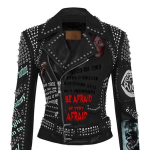 May include: Black leather jacket with silver studs and a punk rock design. The jacket features a zipper closure, a belt, and multiple patches with text and images. The text on the jacket reads "Punk is not just a sound the music punk is a lifestyle be afraid be very afraid".