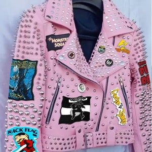May include: Pink leather jacket with silver studs and various band patches, including "Iron Maiden", "Black Flag", "The Monster Squad", "Circle Jerks", and "Operation Ivy".