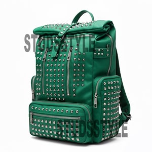 Può includere: Zaino verde con borchie color argento e scomparti multipli con cerniera. Lo zaino ha una maniglia superiore e spallacci regolabili. La parola "STYLE" è parzialmente visibile sul lato sinistro della borsa.