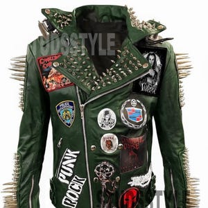 Może przedstawiać: Zielona skórzana kurtka ze srebrnymi kolcami na ramionach i kołnierzu. Kurtka posiada liczne naszywki i przypinki, w tym napisy "PUNK ROCK". Z przodu znajduje się zamek błyskawiczny.