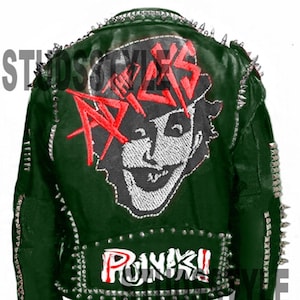 May include: Dark green leather jacket with silver spikes and studs. The back features a graphic of a face and the word "AXLS" in red. The word "PUNK!!" is also displayed. The jacket has a zipper closure and is a punk rock style.