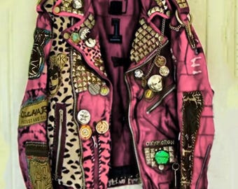 May include: A magenta leather jacket adorned with leopard print panels, metal studs, and various badges. The jacket has a zip fastening, pockets, and the word "OXYMORON" is visible.