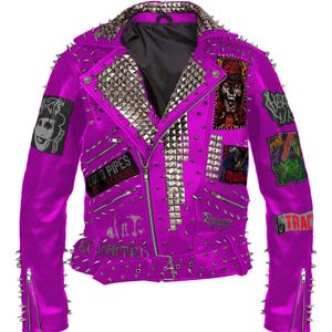 Könnte beinhalten: Eine leuchtend magenta Lederjacke mit silbernen Pyramiden-Nieten und Stacheln. Die Jacke hat mehrere Aufnäher mit grafischen Designs und Text, darunter "LOUD PIPES BECAUSE" und "EXCITED". Reißverschlüsse zieren die Ärmel und die Vorderseite.