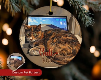 May include: Round ceramic Christmas ornament featuring a calico cat lying on a laptop. The cat has green eyes and brown and orange fur. The ornament has the name "Cali" and the year "2023" printed on it. A smaller image of the cat is in the lower left corner.