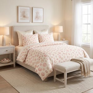 Puede incluir: Un juego de cama con un patrón repetitivo de conchas marinas rosas sobre un fondo crema, que incluye una funda nórdica y dos fundas de almohada a juego. El conjunto se muestra en una cama con cabecero beige en un dormitorio neutro.