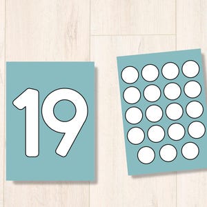 Puede incluir: Una tarjeta azul con el n&uacute;mero 19 impreso en blanco. Una segunda tarjeta azul tiene 25 c&iacute;rculos blancos dispuestos en una cuadr&iacute;cula de 5x5.