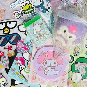May include: A collection of colorful stickers and stationery featuring popular Japanese characters like My Melody and Pochacco. The stickers include a variety of designs, including a penguin with sunglasses, a cupcake, and a heart with wings. The stationery includes a notepad with a green cover and a pink and purple circular notepad with a My Melody design.