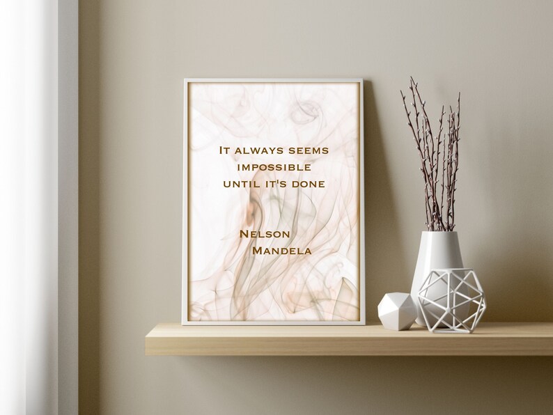 May include: A framed print with a quote by Nelson Mandela on a white background with a subtle brown and gray marbled design. The quote reads "It always seems impossible until it's done."