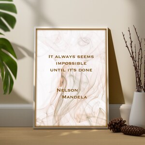 May include: A framed inspirational quote by Nelson Mandela on a white background with a subtle brown marble pattern. The quote reads "It always seems impossible until it's done."
