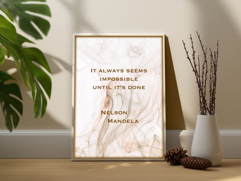 May include: A framed inspirational quote by Nelson Mandela on a white background with a subtle brown marble pattern. The quote reads "It always seems impossible until it's done."