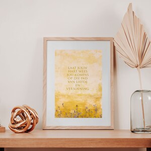 May include: A framed print with a yellow watercolor background and the text "LAAT JOUW HART WEES JOU KOMPAS OP DIE PAD VAN LIEFDE EN VERSOENING" in gold lettering.