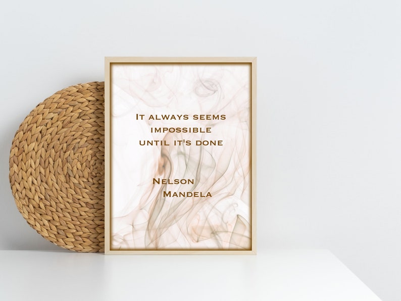 May include: A framed print with a quote by Nelson Mandela: "It always seems impossible until it's done." The background is a soft, abstract design in shades of beige and white.