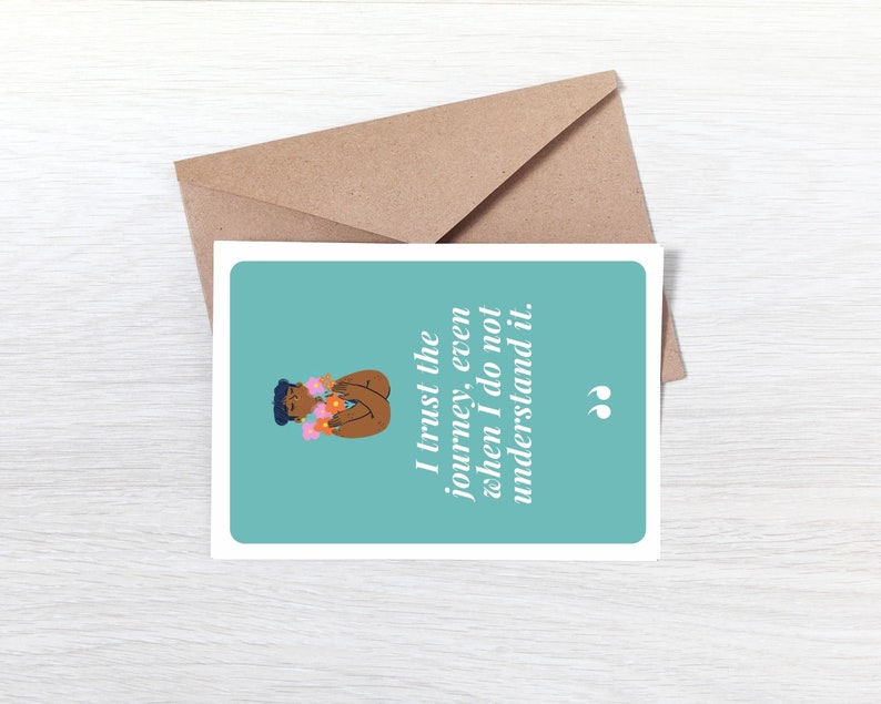 May include: A teal blue card with a quote that reads "I trust the journey, even when I do not understand it." The quote is in white text and is surrounded by a white border. The card features a cartoon illustration of a person with brown skin wearing a flower crown.