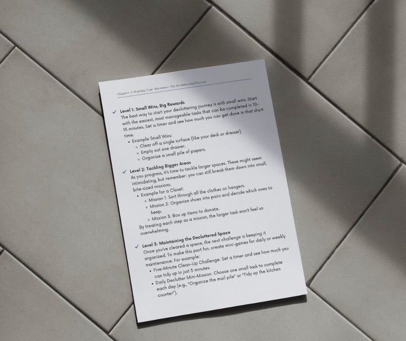 May include: A white printed page with text about decluttering, titled "Chapter 2: Mastering Your Momentum: The Decluttering Treasure". The text is organized into levels with small tasks, including clearing surfaces and organizing items.