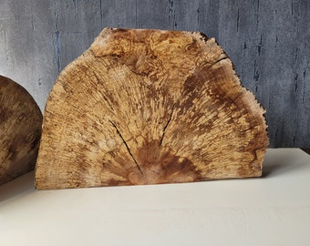 Könnte beinhalten: Zwei große, natürliche Holzscheiben in hellbrauner Farbe mit einem einzigartigen Maserungsmuster. Das Holz hat eine raue, strukturierte Oberfläche und scheint ein Querschnitt eines Baumstamms zu sein.