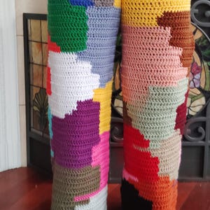 May include: Crocheted pants featuring a patchwork design in a variety of colors, including green, blue, yellow, pink, and red. The handmade pants have a unique, textured appearance, showcasing the individual stitches and color blocks.