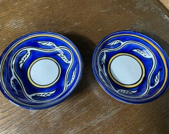 Könnte beinhalten: Zwei blaue und weiße Keramikschalen mit einem gelben und schwarzen Blumendesign. Die Schalen sind leer und haben einen weißen Innenraum.