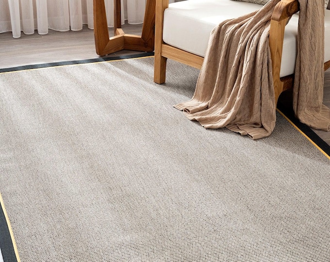 A sisal-weave rug featuring a natural-colored base and dual-tone striped borders in gold and black; suitable for kitchens and living rooms.