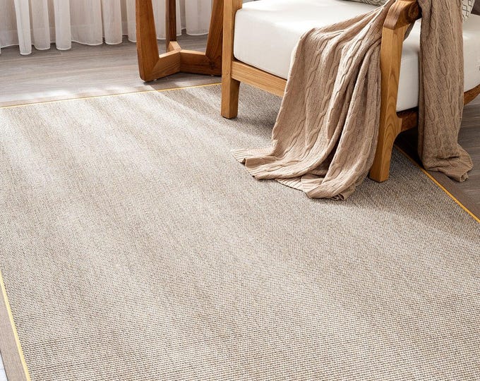 A sisal-weave rug featuring a natural-colored base and dual-tone border strips in gold and beige; suitable for kitchens and living rooms.