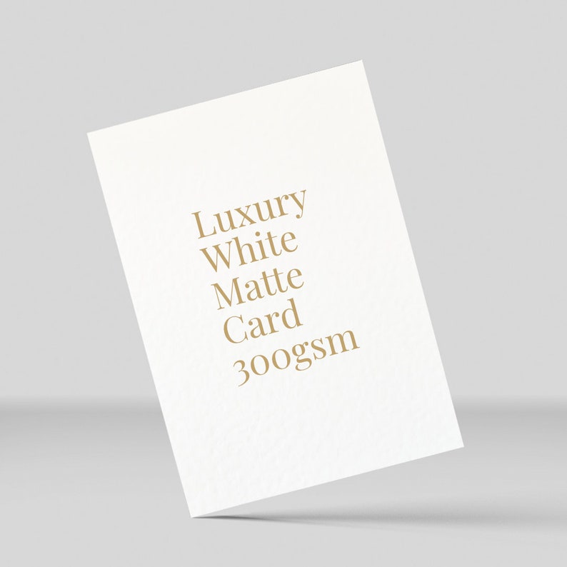 K&ouml;nnte beinhalten: Eine wei&szlig;e Karte mit dem Text "Luxury White Matte Card 300gsm" in Gold gedruckt.
