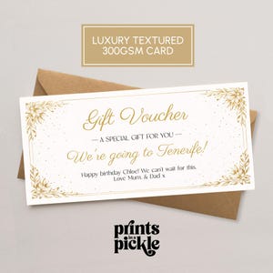 May include: A gold-coloured gift voucher with floral detailing and the text "Gift Voucher" and "We're going to Tenerife!" on a white background. The voucher is inside a brown envelope. The card is labelled "LUXURY TEXTURED 300GSM CARD".