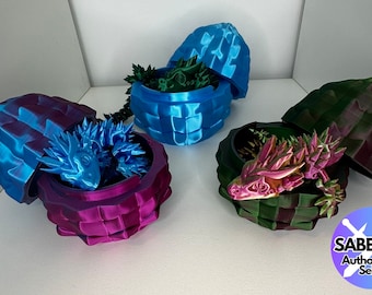 May include: Three 3D printed dragon eggs, each with a different color scheme. The eggs are open, revealing a dragon inside. The eggs are made of a textured material and have a glossy finish. The dragons are all different colors, with one being blue, one being green, and one being pink.