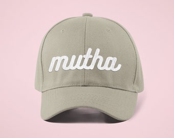 May include: A light gray baseball cap with the word "mutha" embroidered in white on the front.