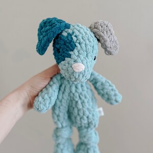Pu&ograve; includere: Un giocattolo di peluche all'uncinetto a forma di cane. Il cane &egrave; blu e verde con le orecchie grigie. Il cane ha un naso bianco e occhi neri.