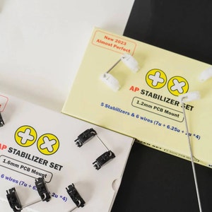 Könnte beinhalten: Zwei Pakete mit Tastaturstabilisatoren, eines weiß und eines gelb. Das weiße Paket enthält schwarze Stabilisatoren und das gelbe Paket enthält weiße Stabilisatoren. Beide Pakete tragen den Text "AP Stabilizer Set" und die Größe der PCB-Montage.