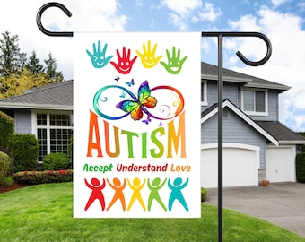 May include: A white garden flag with a rainbow-colored butterfly and the word "AUTISM" in rainbow colors. The text "Accept Understand Love" is below the word "AUTISM". There are five rainbow-colored handprints at the top of the flag and five rainbow-colored stick figures at the bottom.