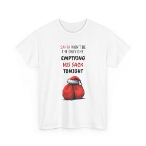 May include: White t-shirt featuring the text "SANTA WON'T BE THE ONLY ONE EMPTYING HIS SACK TONIGHT" in red and black. The design includes a red sack with a Santa hat illustration.