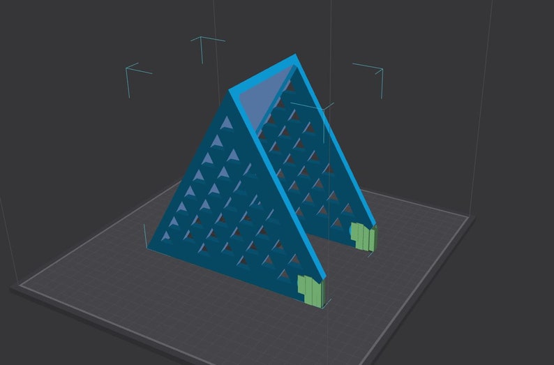 May include: A teal-colored, triangular structure with a geometric pattern of small triangles cut out of the sides. The structure has a flat base and two green rectangular supports. The background is a dark gray.