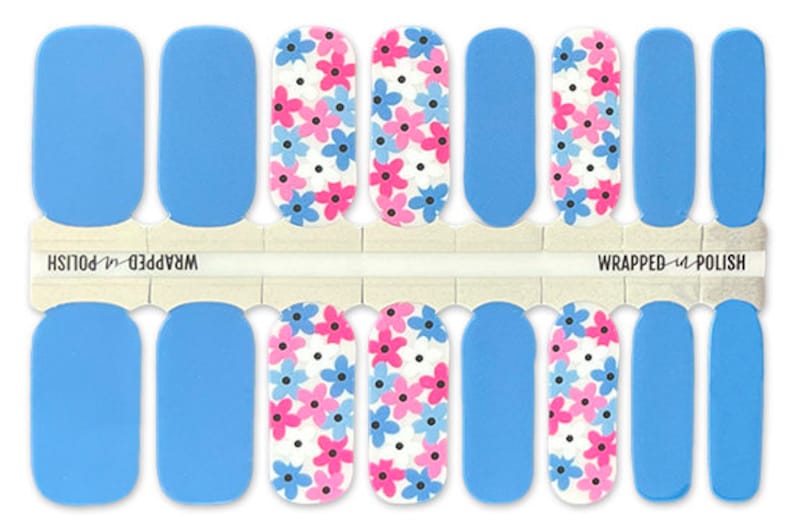 May include: A set of 10 nail wraps featuring a blue background with a white and pink floral pattern. The nail wraps are labeled "Wrapped Up Polish".